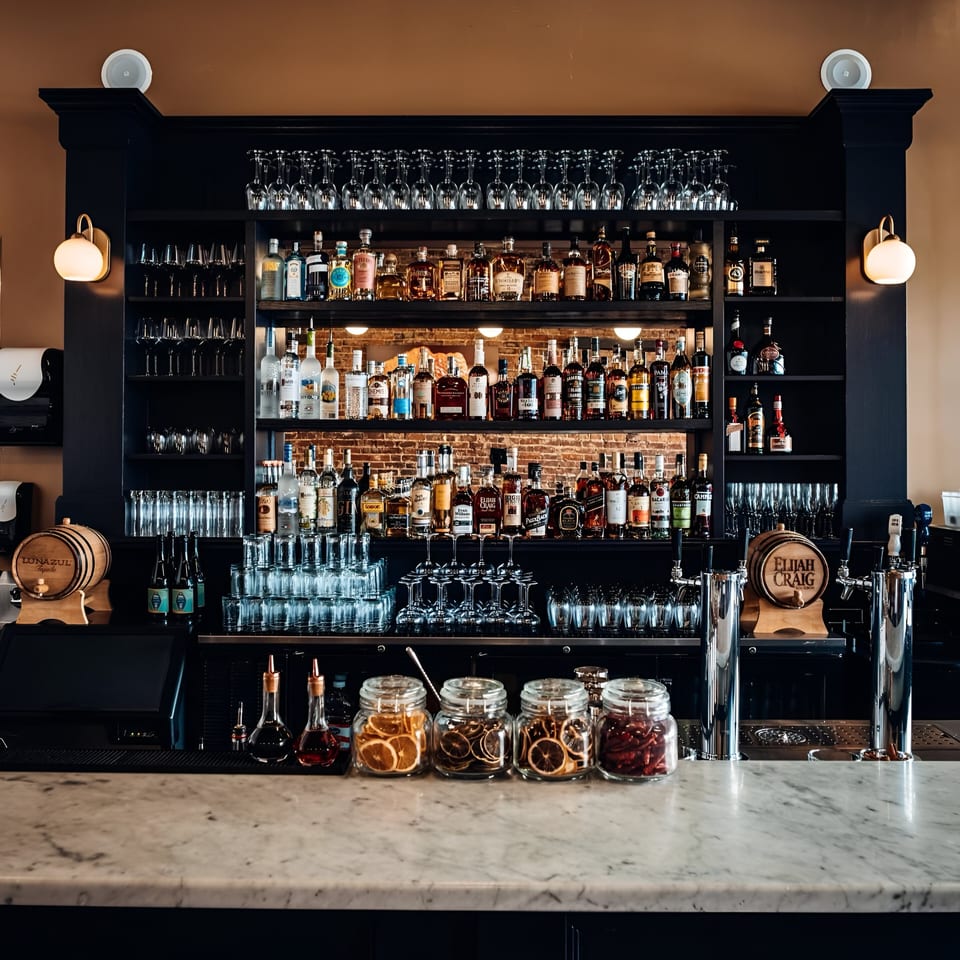 Honeycomb Cafe's well-stocked bar with various liquor bottles, glassware, and garnishes on a marble counter.