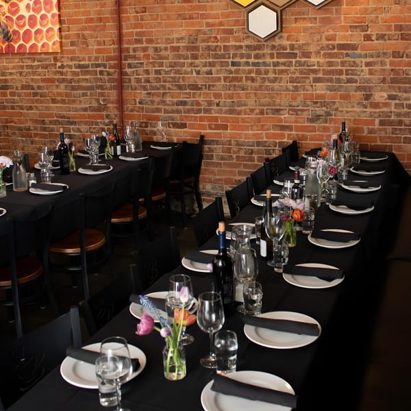 Long tables set with black tablecloths, white plates, wine glasses, and small flower arrangements.
