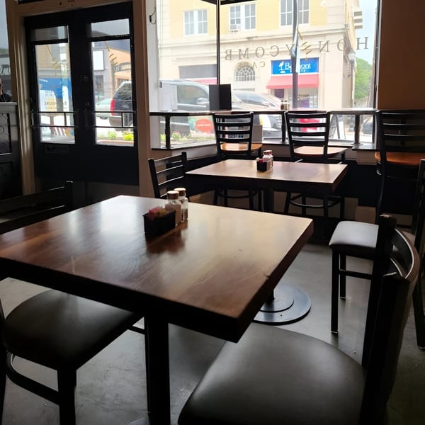 Interior of Honeycomb Cafe with empty tables and chairs, and a street view through the windows.